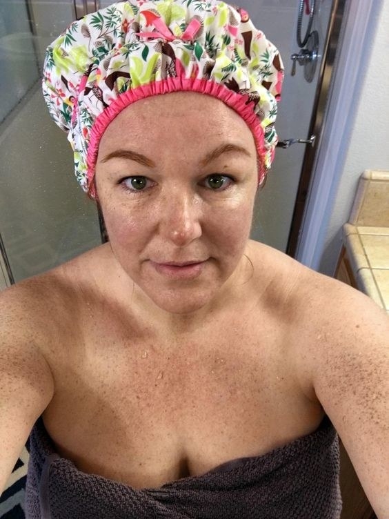 reviewer wrapped in a towel wearing a patterned shower cap