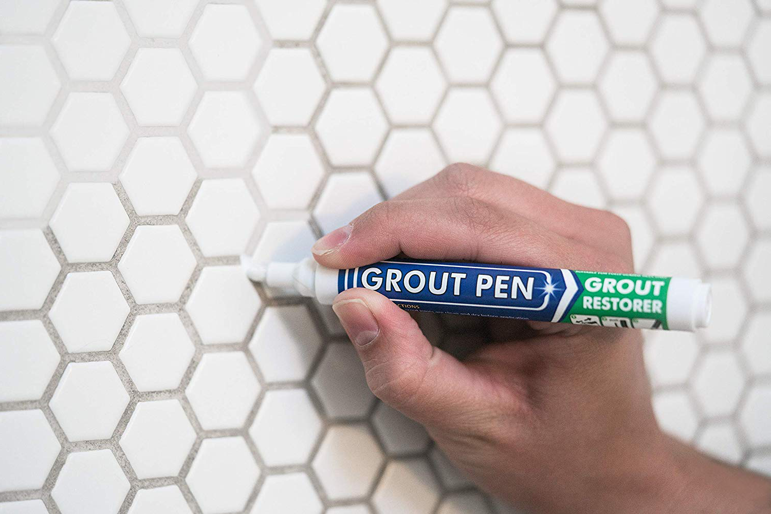 Model using a small pen to make grout white again 