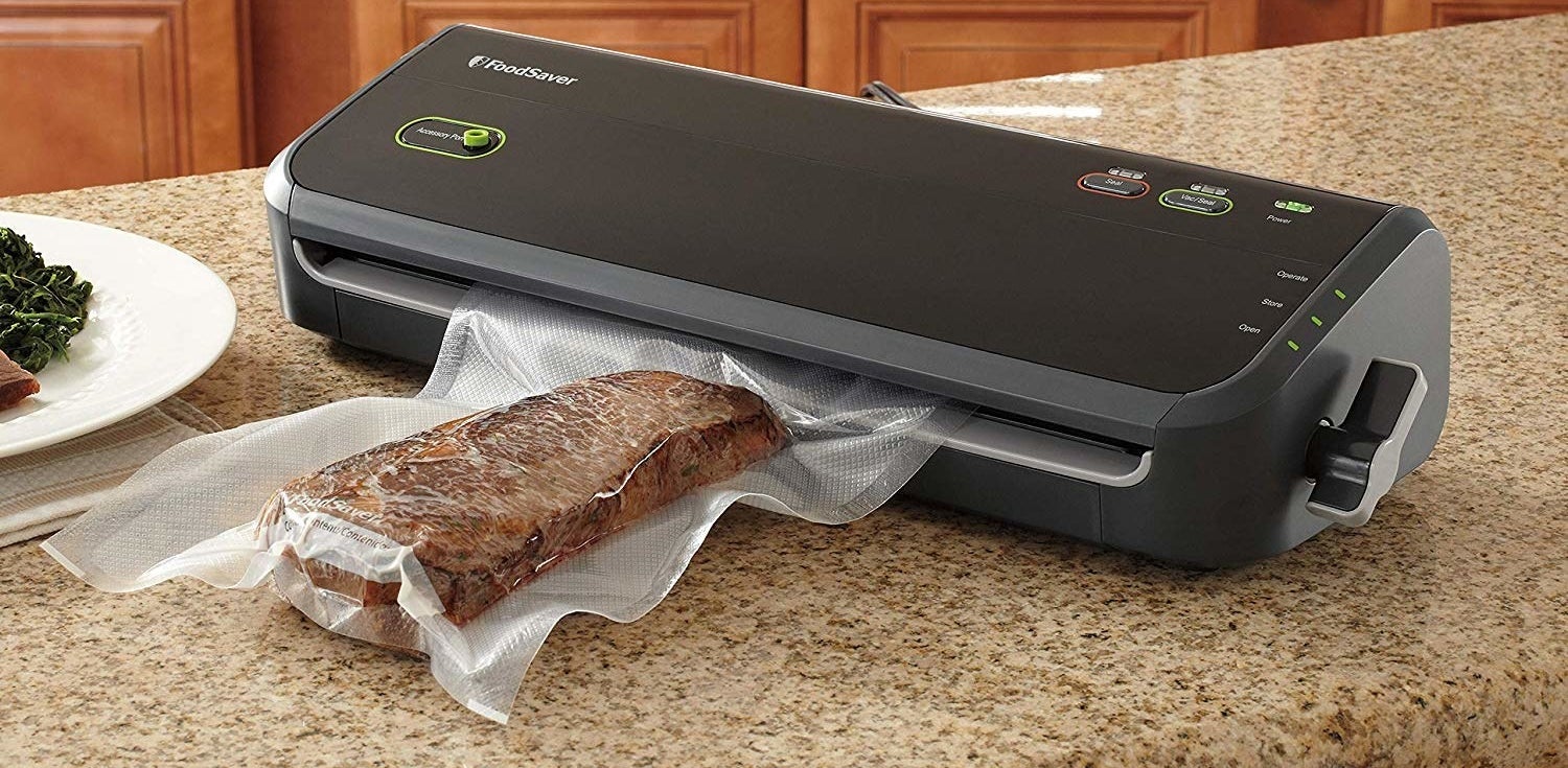 kitchen counter with a vacuum sealing machine sealing a hunk of meat
