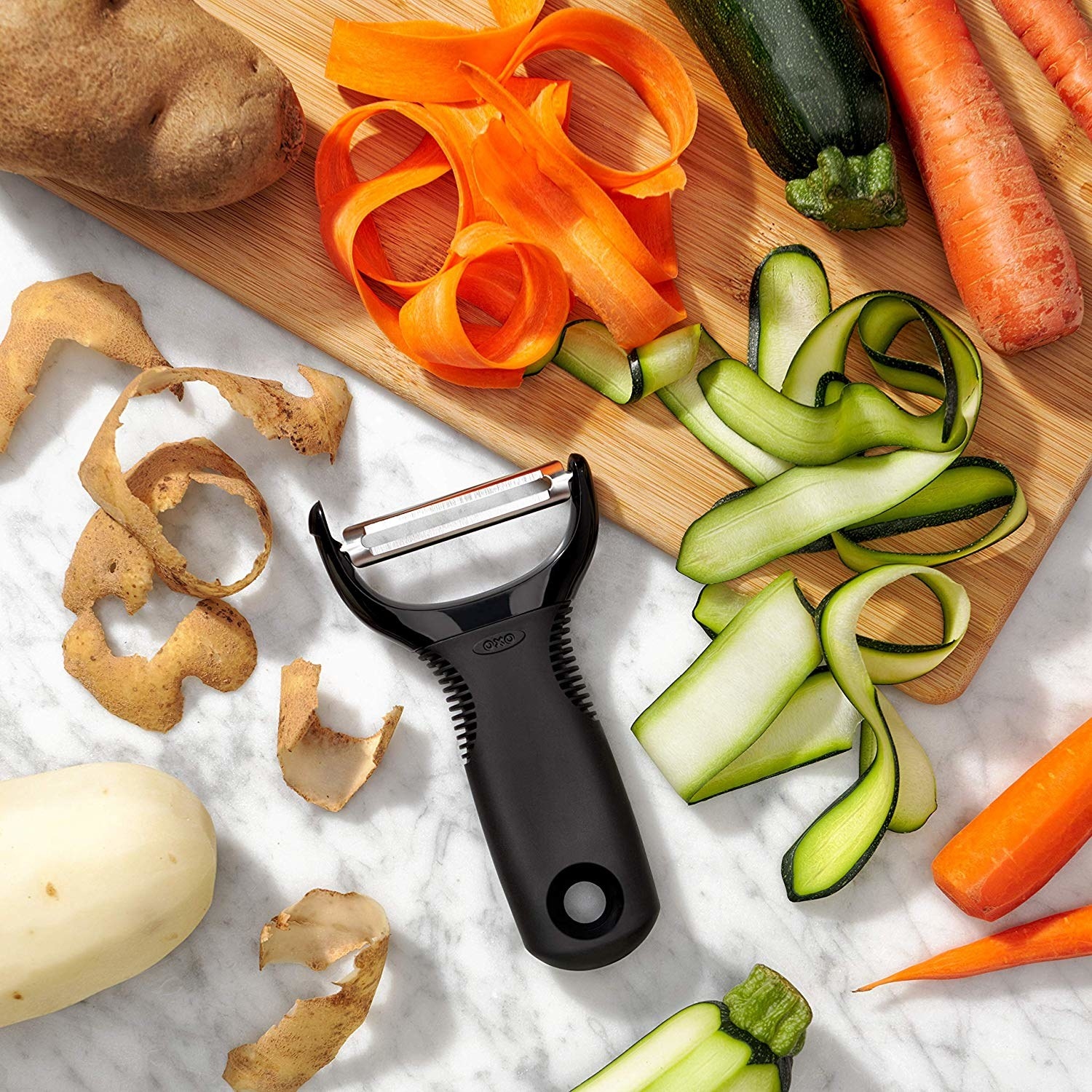 the peeler on a surface with peeled veggies