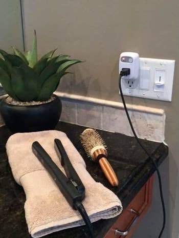 a straightener in a bathroom plugged in the outlet