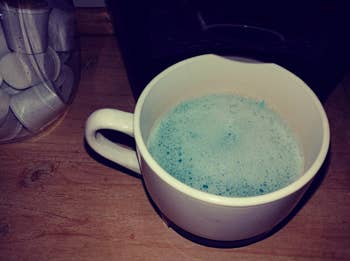 Reviewer photo of their coffee mug filled with the blue cleaning agent that runs through the machine