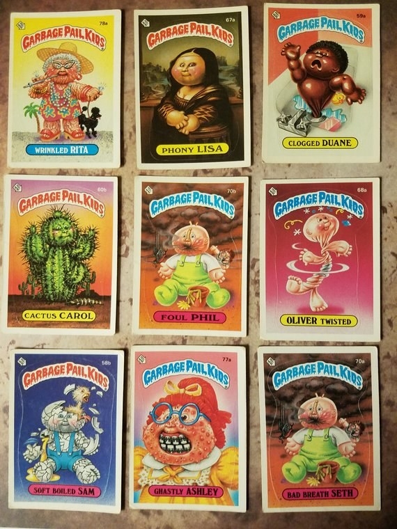 Nine different Garbage Pail Kids cards laid out on table