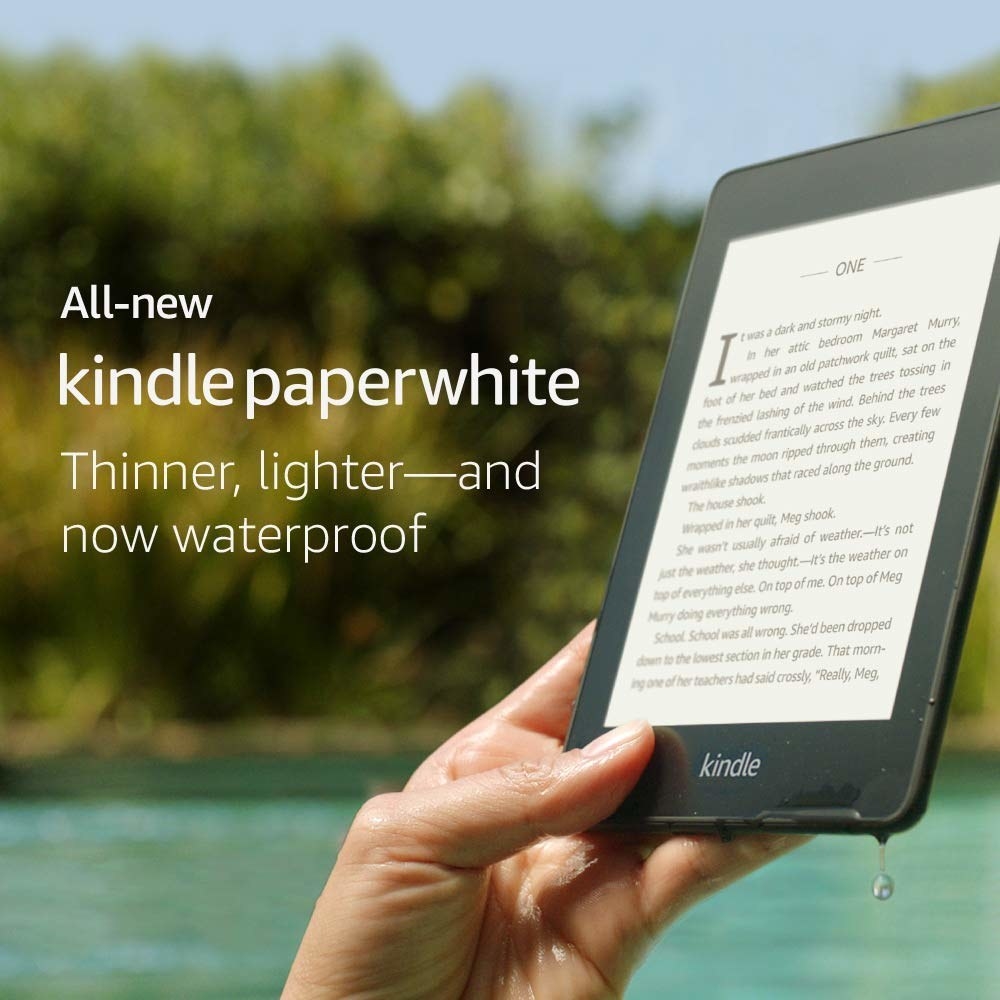 A hand holding the kindle in black in a body of water