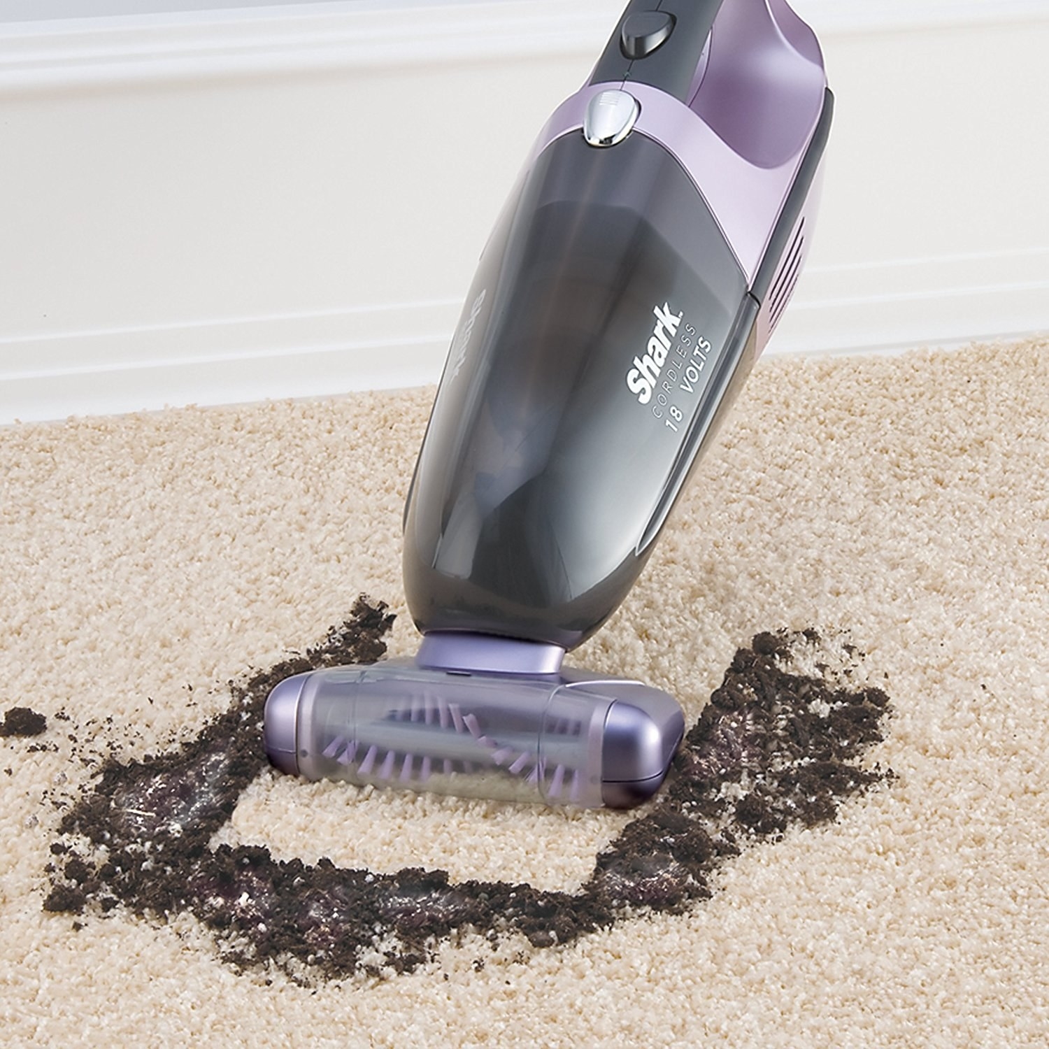 The Shark vacuum sucking up dirt from a carpeted floor