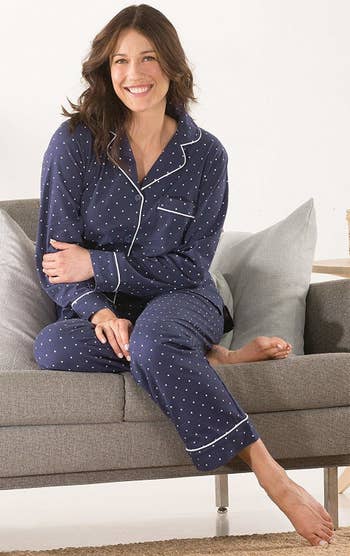 Model wearing the pajamas in blue with white trim and small white polka dots