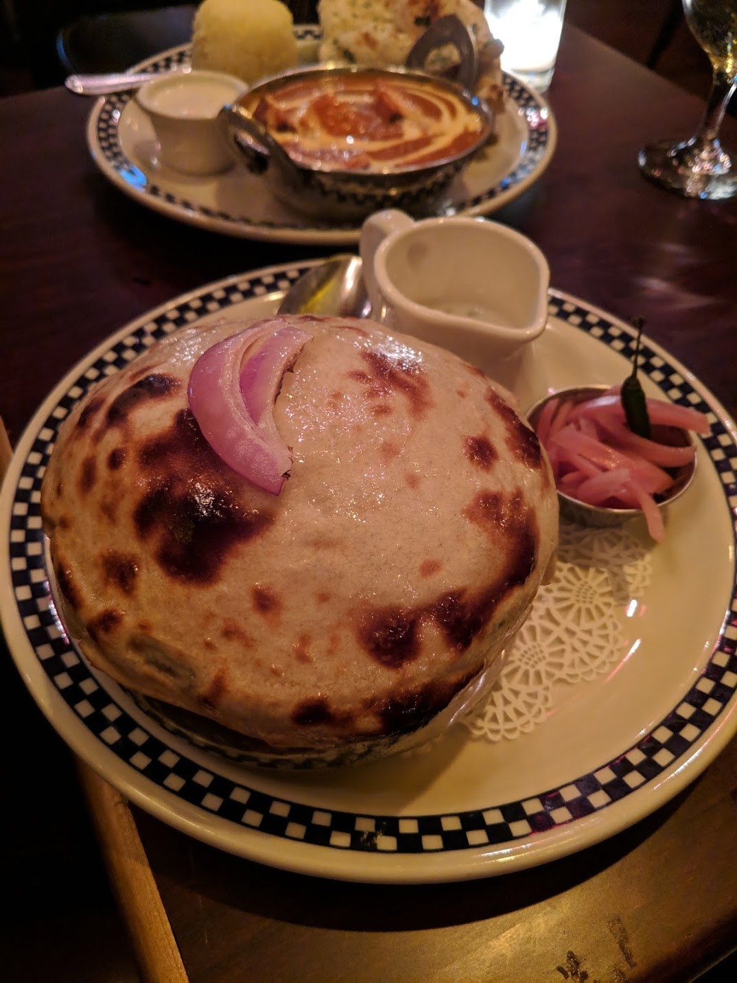 Biryani, aka "The Royal Rice," was brought to India from Persia through Arab trade routes in the 1600s. At The Drunken Munkey, the Biryani takes a whole new meaning. It's served with buttery, doughy bread on top like pot pie. Underneath the buttery crust is flavorful basmati rice seasoned with various spices and then fried with lamb, vegetables, and other seasoning. The dish is served with a side of raita that you pour over the rice like you would with souffle.