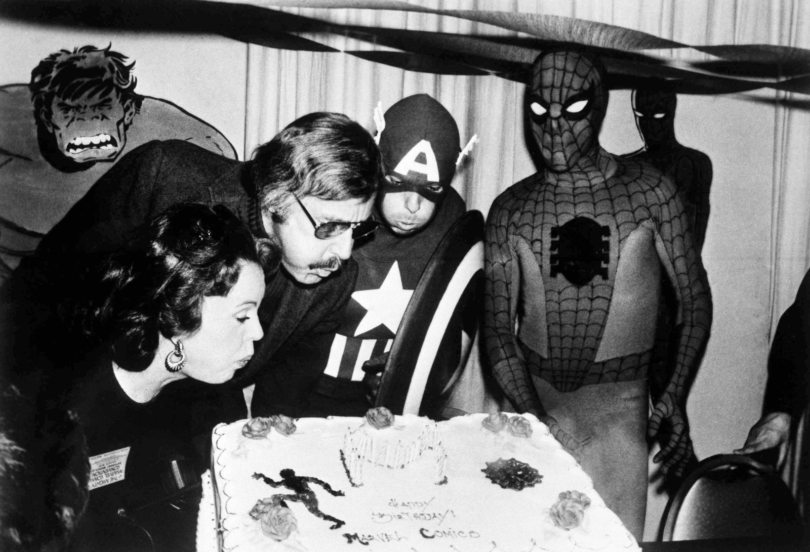 Mighty Marvel comic book publisher Lee (second from left) and his wife, Joan (far left), blow out the candles on the Marvel Comics birthday cake at opening day ceremonies of the first-ever Mighty Marvel Comic Book Convention on March 22, 1975, in New York.
