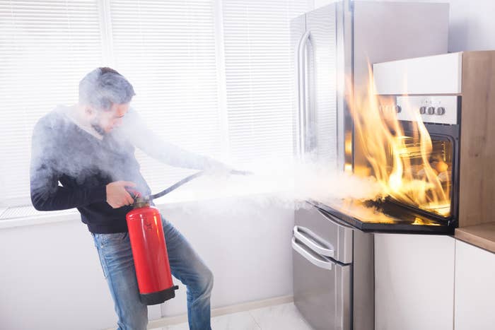 A man extinguishing an oven fire in his kitchen