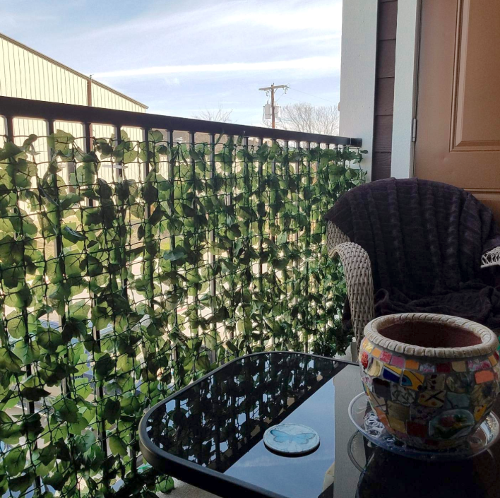A reviewer's balcony with the ivy hung; it comes on a (rolled-up) plastic grid with the leaves all over it. You can just barely make out a car on the other side, the leaf coverage is so good