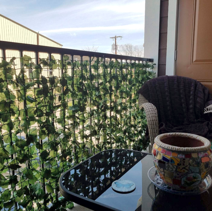 A reviewer&#x27;s balcony with the ivy hung; it comes on a (rolled-up) plastic grid with the leaves all over it. You can just barely make out a car on the other side, the leaf coverage is so good