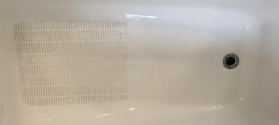 A reviewer&#x27;s bathtub half cleaned to show the difference the scrubbers made
