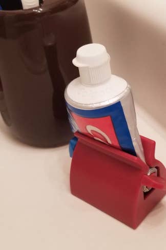 reviewer's photo of their toothpaste in the red holder 
