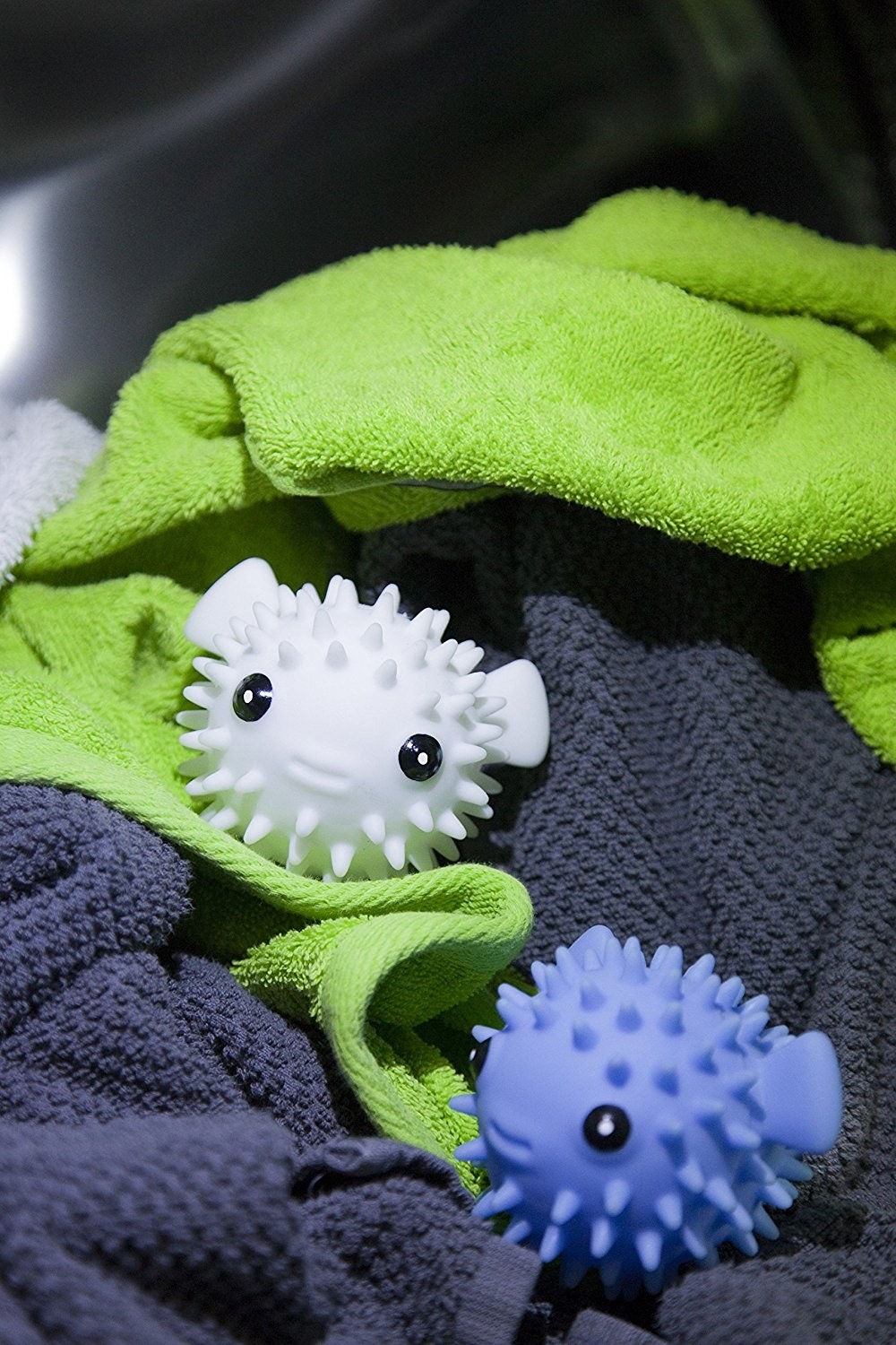 one white and one blue puffer fish-shaped dryer ball sitting in laundry