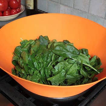 Spinach cooking down in a pan; the frywall keeps it all contained