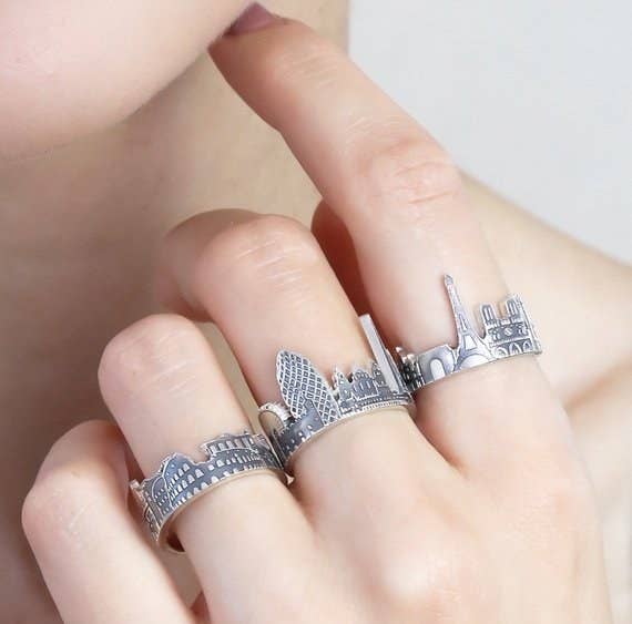 model wearing silver rings shaped like the skylines of rome, london, and paris