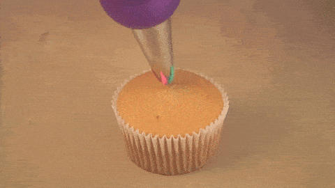 Animated gif of three colors of icing, swirled, being pumped on a cupcake at once
