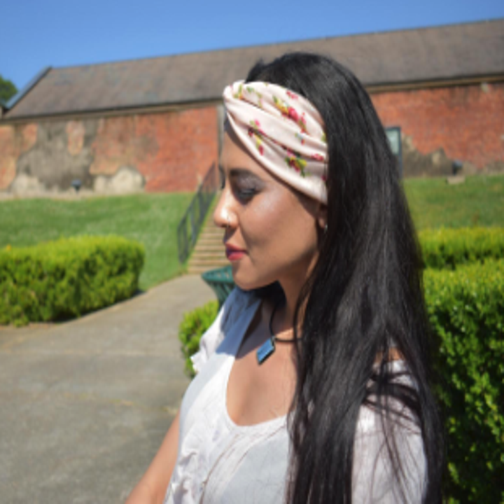 a reviewer wearing a tan headband with a knot in the middle and small florals on it