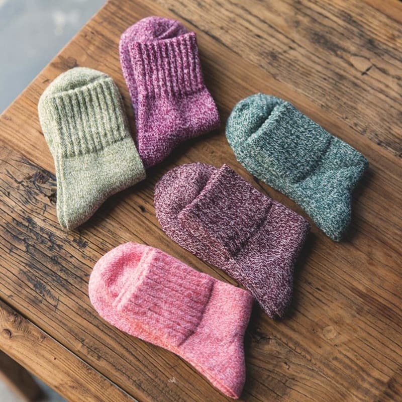 Five pairs of knit socks in a variety of colors folded and set on a table