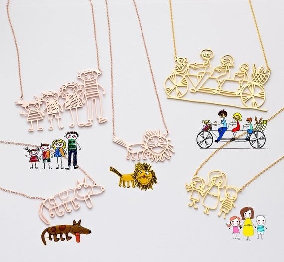 Several children&#x27;s drawings next to rose gold and gold pendant necklaces of them