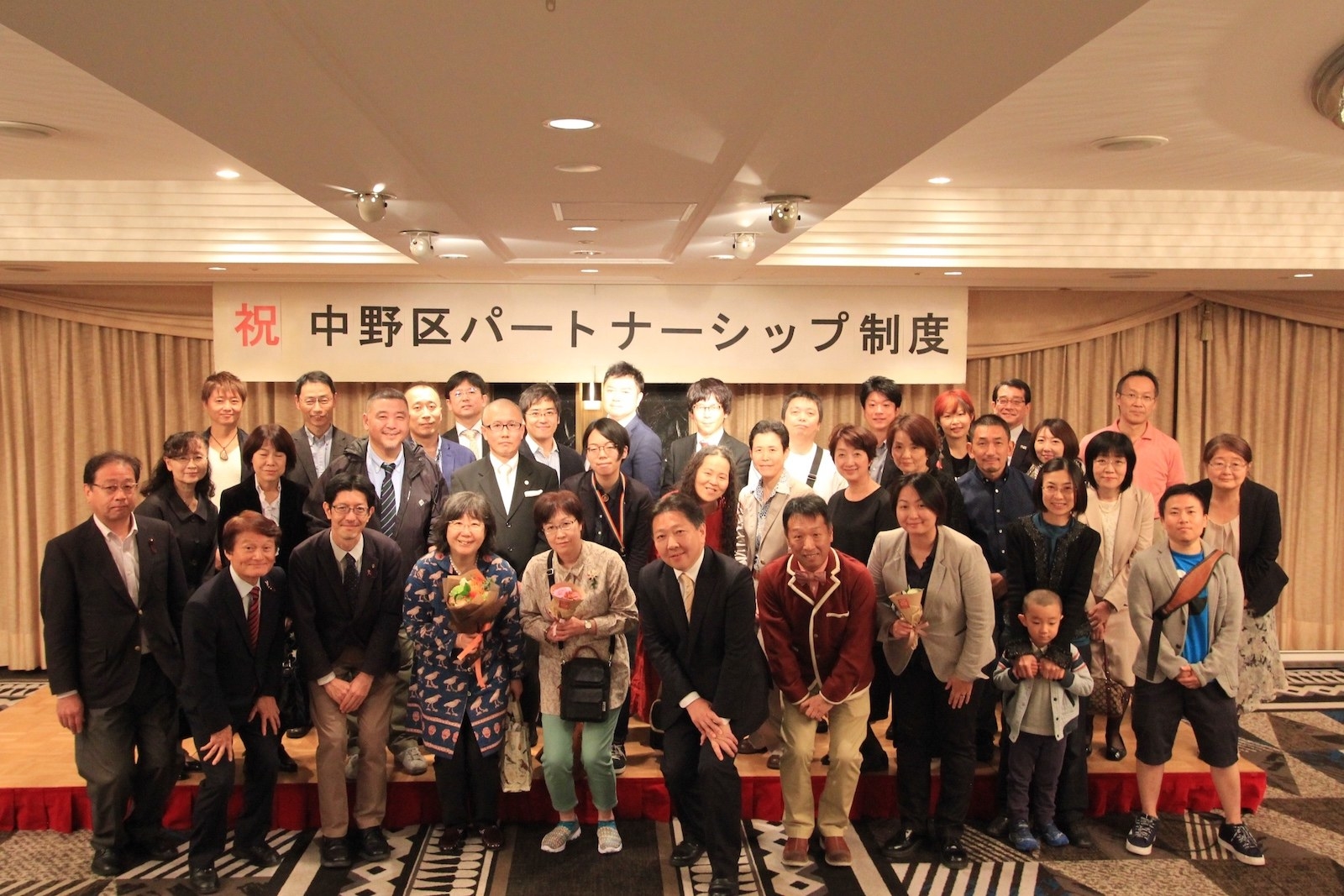 中野区の当事者グループ(中野にじねっと、後述)が主宰し、区長や区議、区の職員も来賓に迎えて10月21日に開かれた制度のスタートを祝うパーティー。中央は酒井直人・中野区長、向かって左隣が1号の宣誓をした女性カップル。