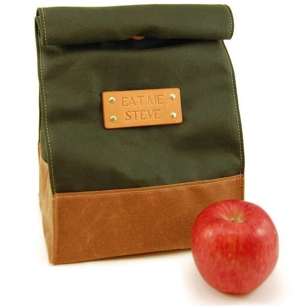 The leather and fabric roll-top lunch bag that says "eat me steve" on the nameplate
