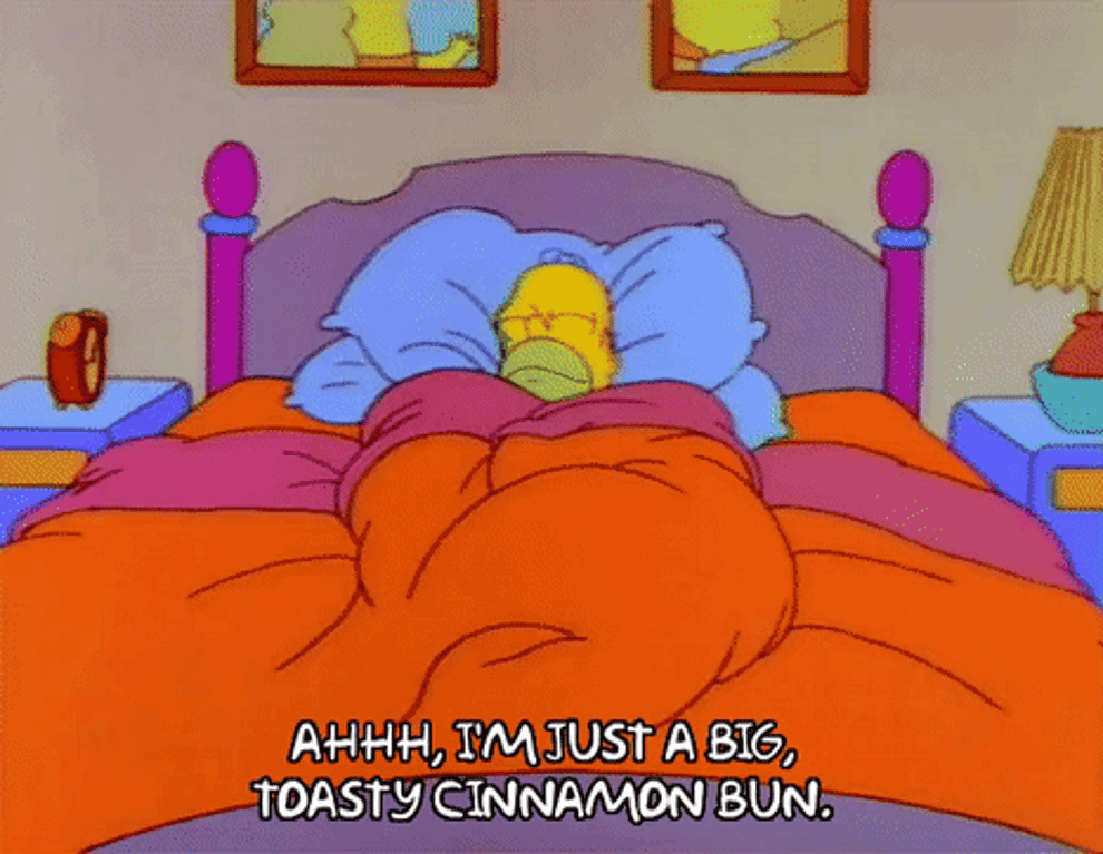Homer Simpson from the Simpsons snuggled up in bed and saying &quot;Ahhh, I&#x27;m just a big, toasty cinnamon bun&quot;