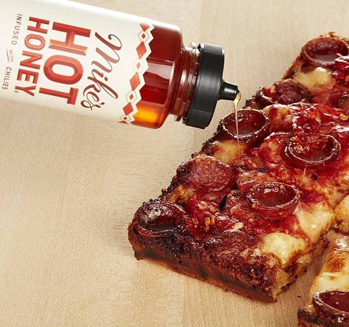 hot honey being drizzled on pepperoni pizza
