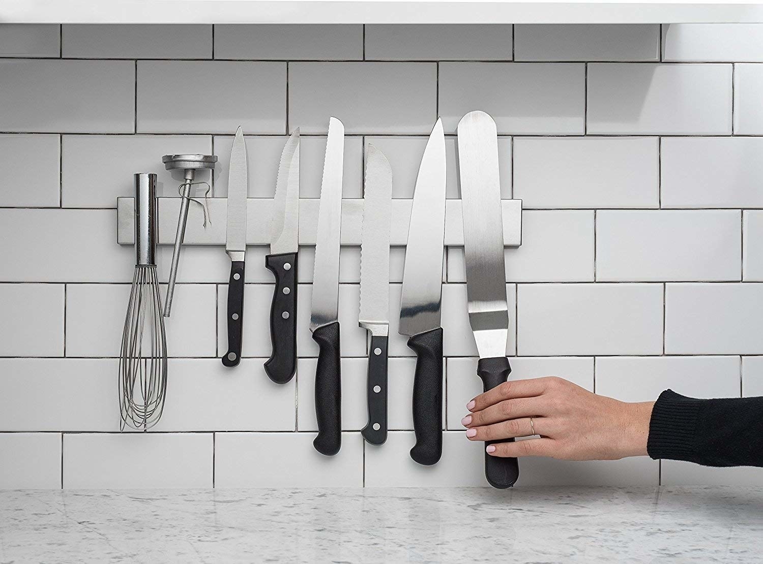 the long rectangle strip on a wall with assorted knives and kitchen tools on it
