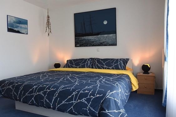 reviewer&#x27;s bed with the navy blue bed set on it and white tree branches all over it 