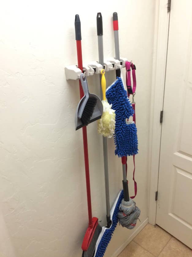 organizer hung behind reviewer's door; holding three brooms and mops plus dog's leash and duster on the hooks