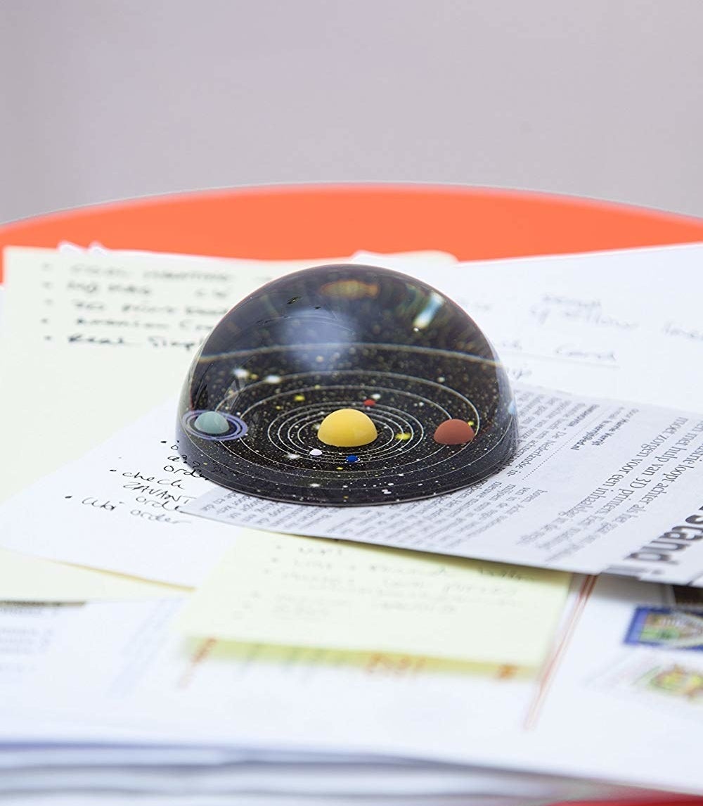 solar system dome shape paperweight on stack of papers