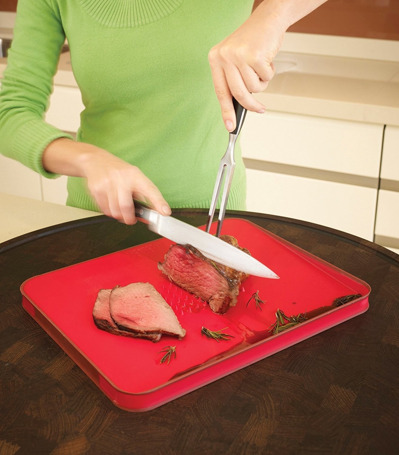 Model cuts meat on the cutting board, using the spikes to keep it in place