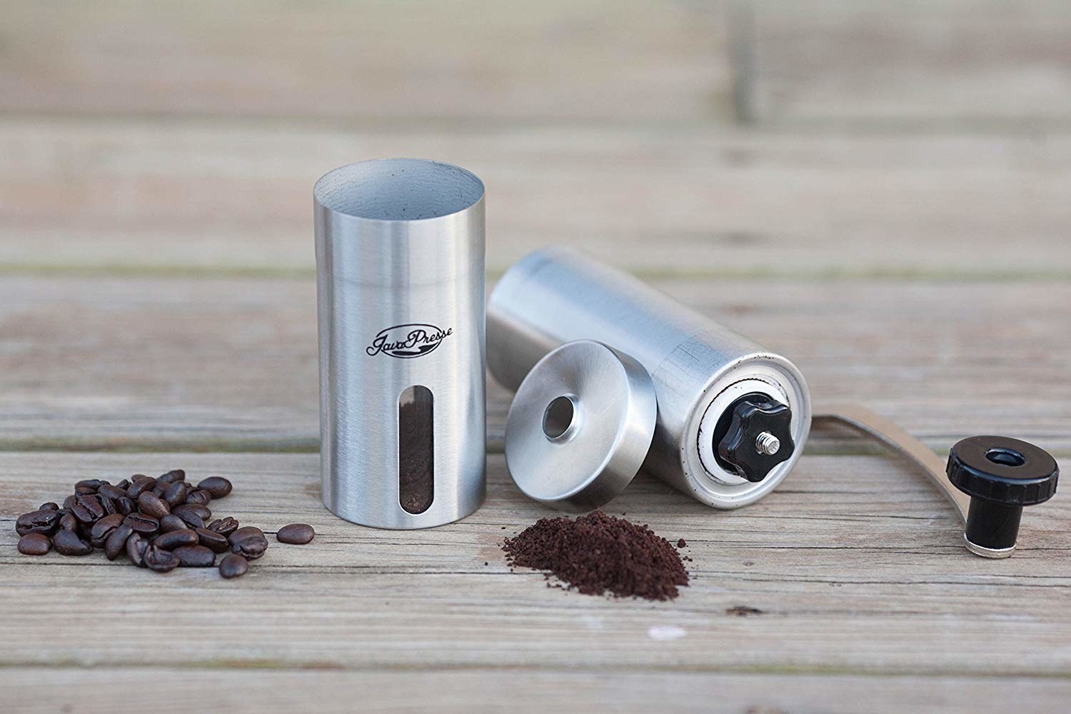 The grinder surrounded by coffee beans and an example of some that it has ground.