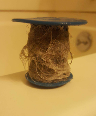 reviewer pic of a bunch of hair around the Tubshroom that the product caught before it going down the drain