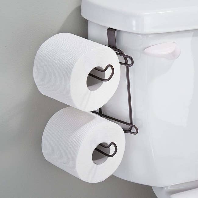 toilet with a holder for two spare rolls on toilet paper on the side of the toilet tank 