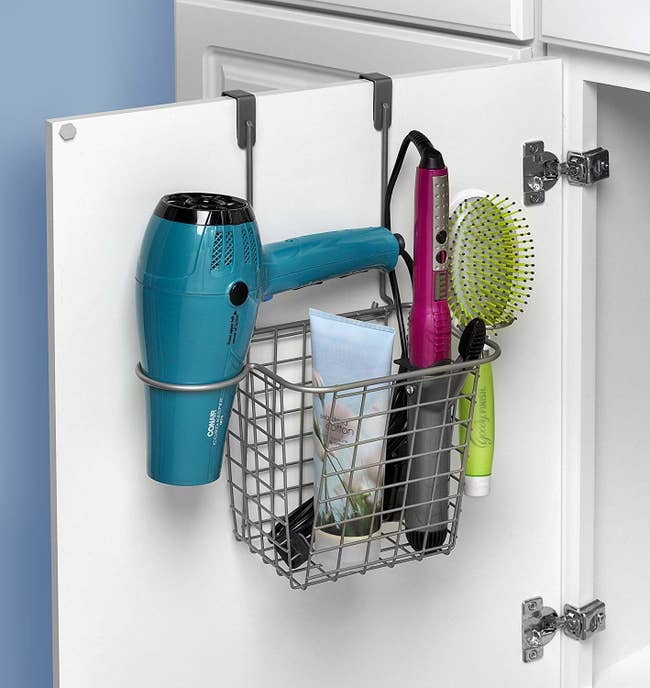 open bathroom cabinet door with basket-like over-the-door hanging organizer filled with hair tools