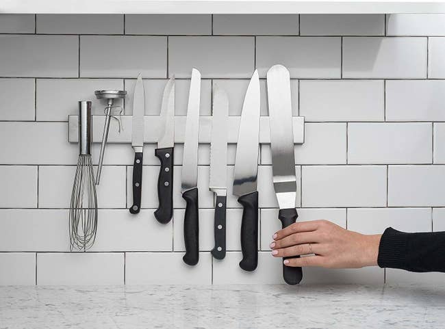 The wall-mounted stainless-steel strip holding up a set of knives and whisk