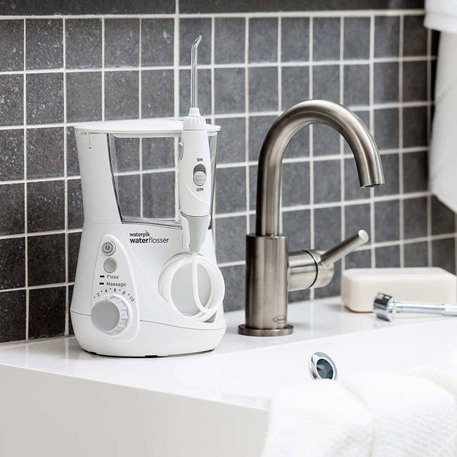 the water flosser charging on reservoir stand on bathroom sink