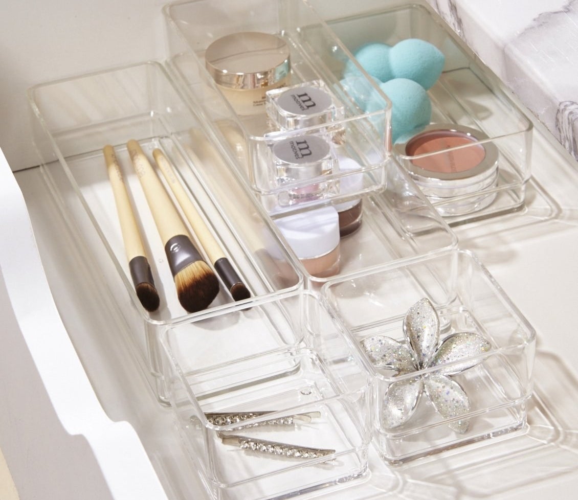 Six clear bins in a drawer organizing an array of beauty supplies
