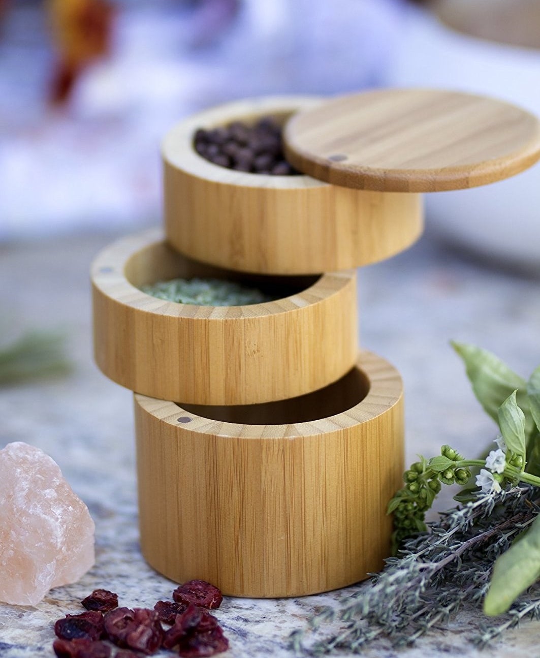 a close up of the cylindrical three tier bamboo storage box with different spices inside