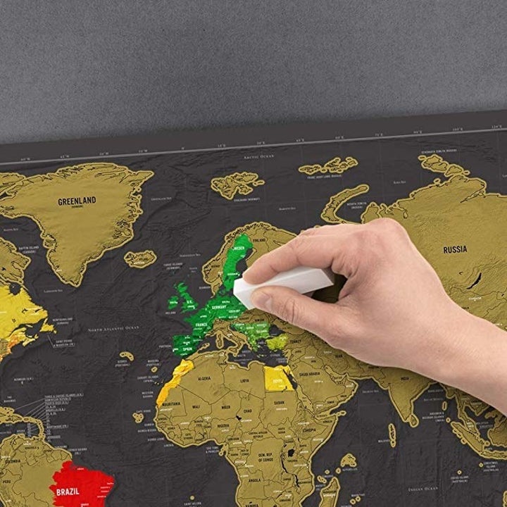 A hand scratching off the coating on countries in Europe