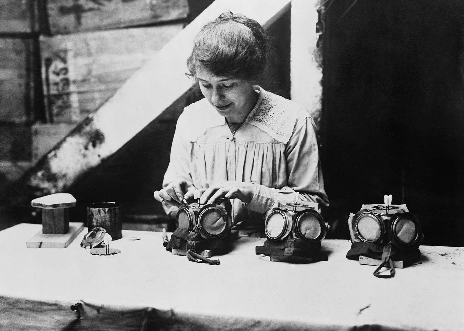 A war worker fixes nose clips onto gas masks at a factory in London, circa 1918.