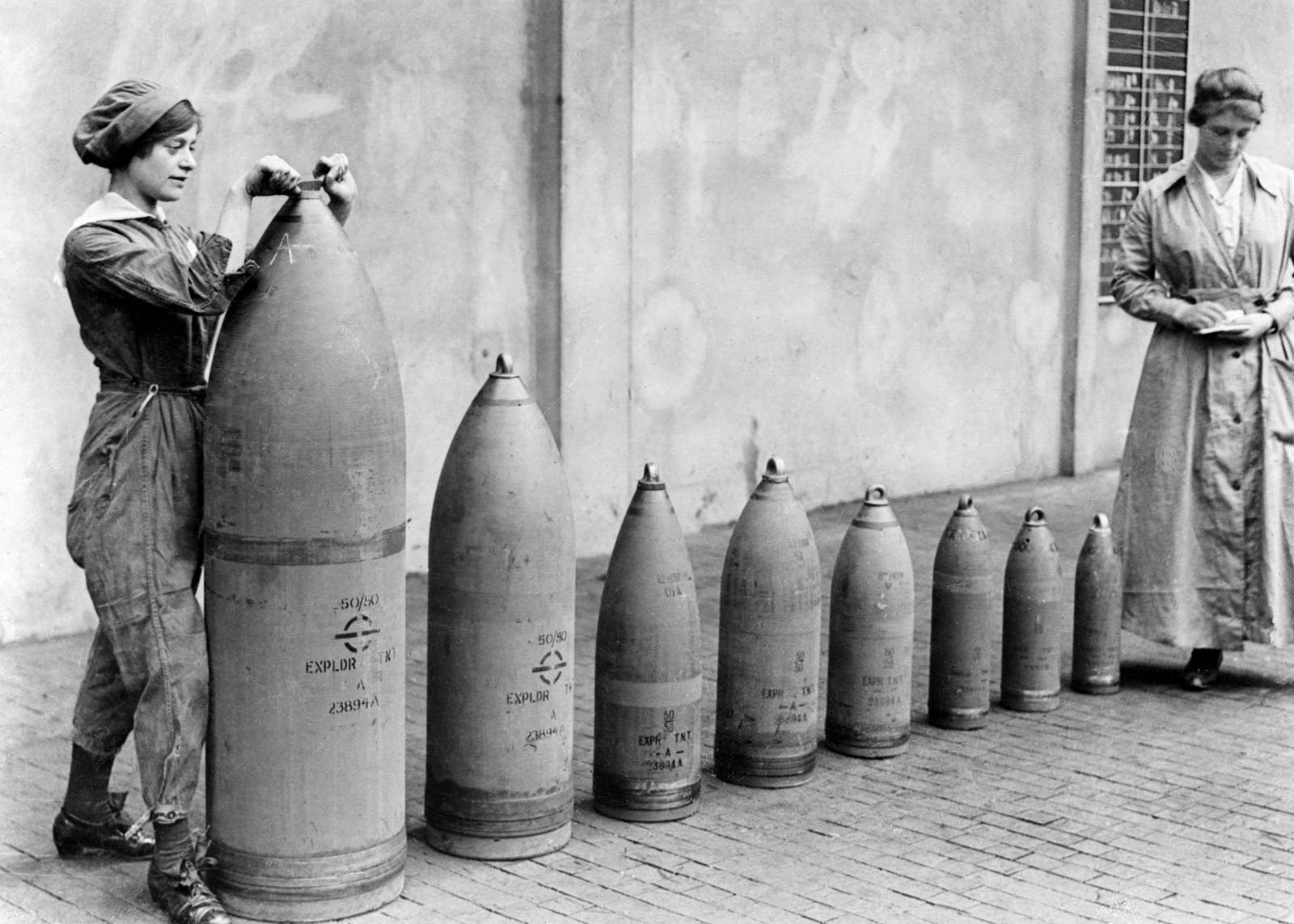 Two munitions workers stand beside examples of the shells produced at the National Shell Filling Factory in England, circa 1917.