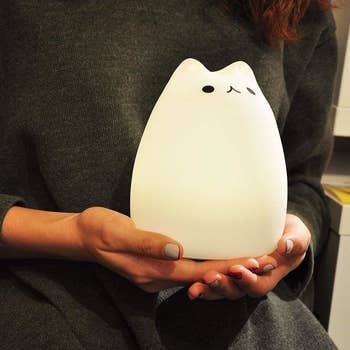 Hands holding the rounded cat-shape light glowing white