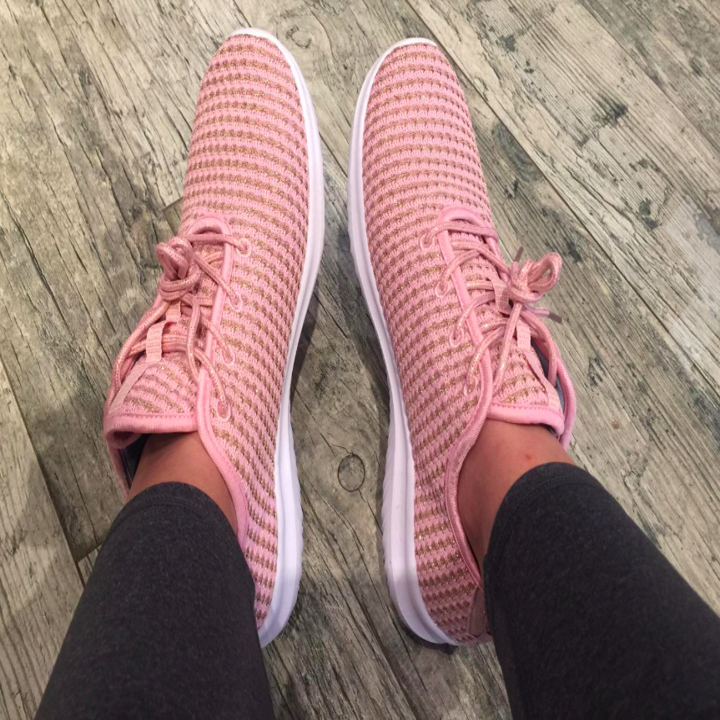 A customer review photo of a person wearing the sports sneakers in pink