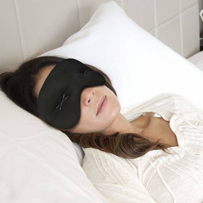 person sleeping in bed with eye mask on face