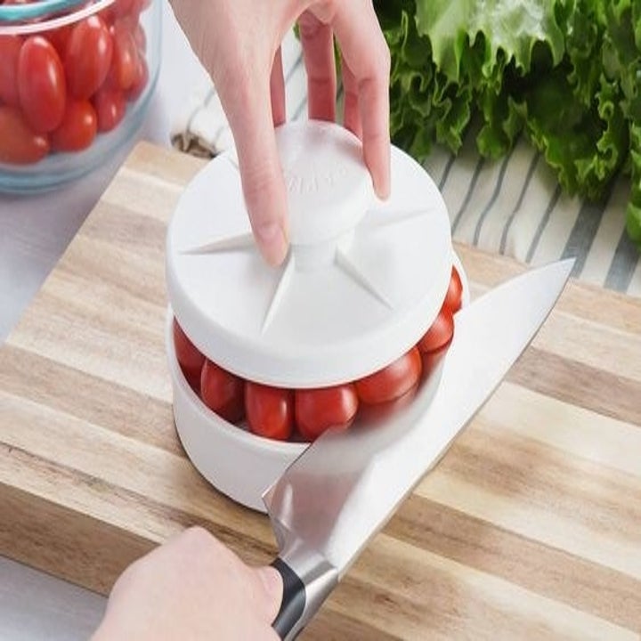 The tool being used to slice cherry tomatoes
