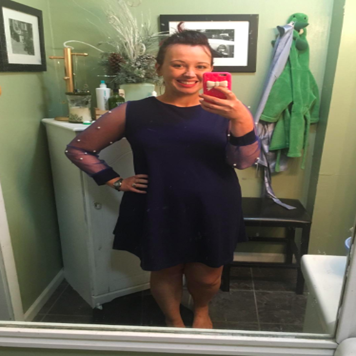 A reviewer wearing the dress in navy with sheer pearl-embellished sleeves