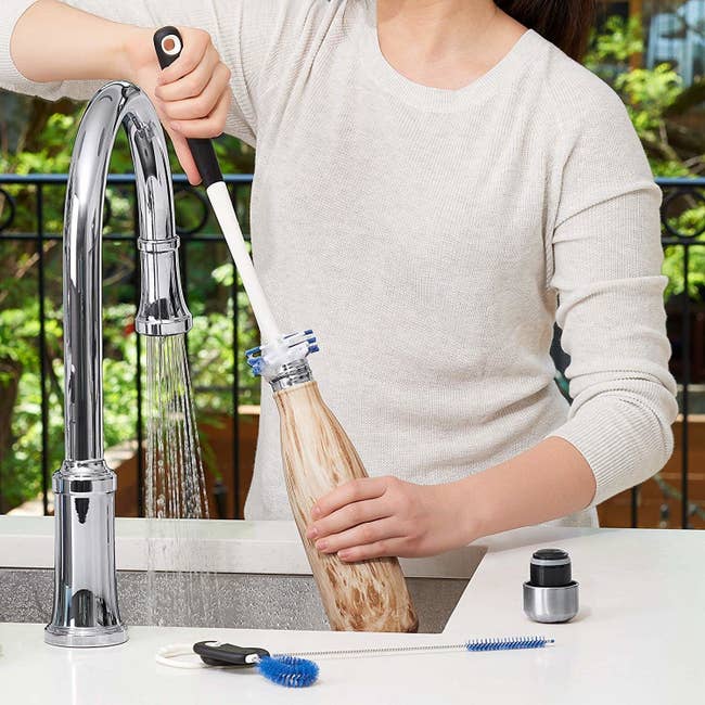 model using the long-handled bottle brush to clean out a tall S'well water bottle